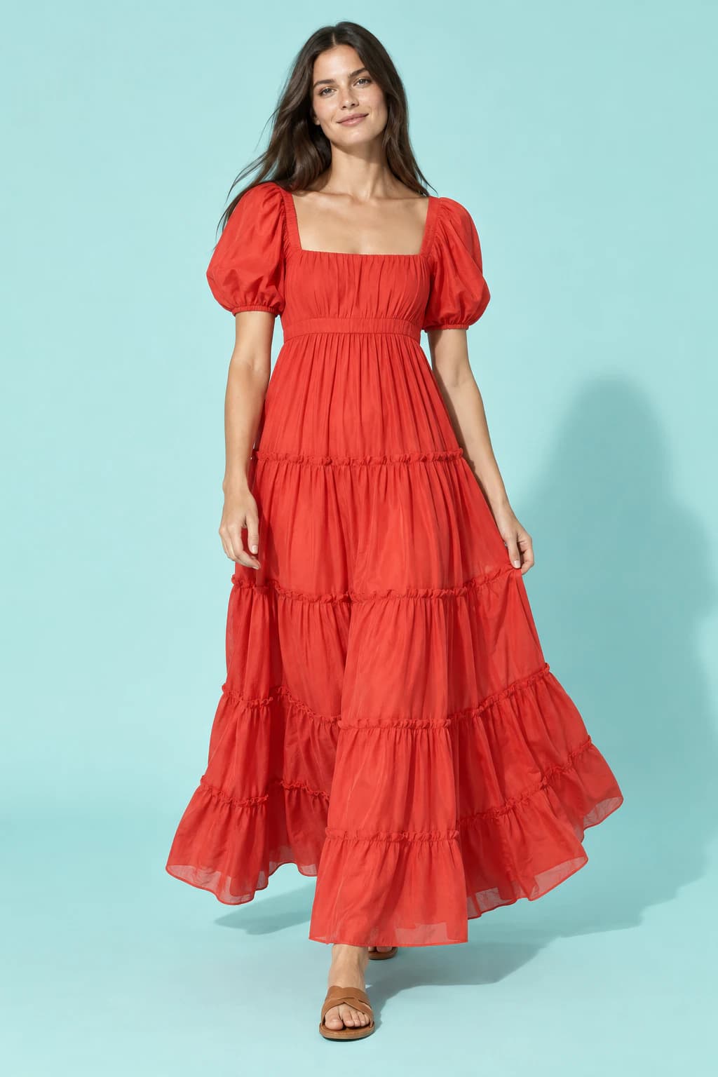 Model in a tiered poppy-red ruffle maxi dress on a pale aqua backdrop