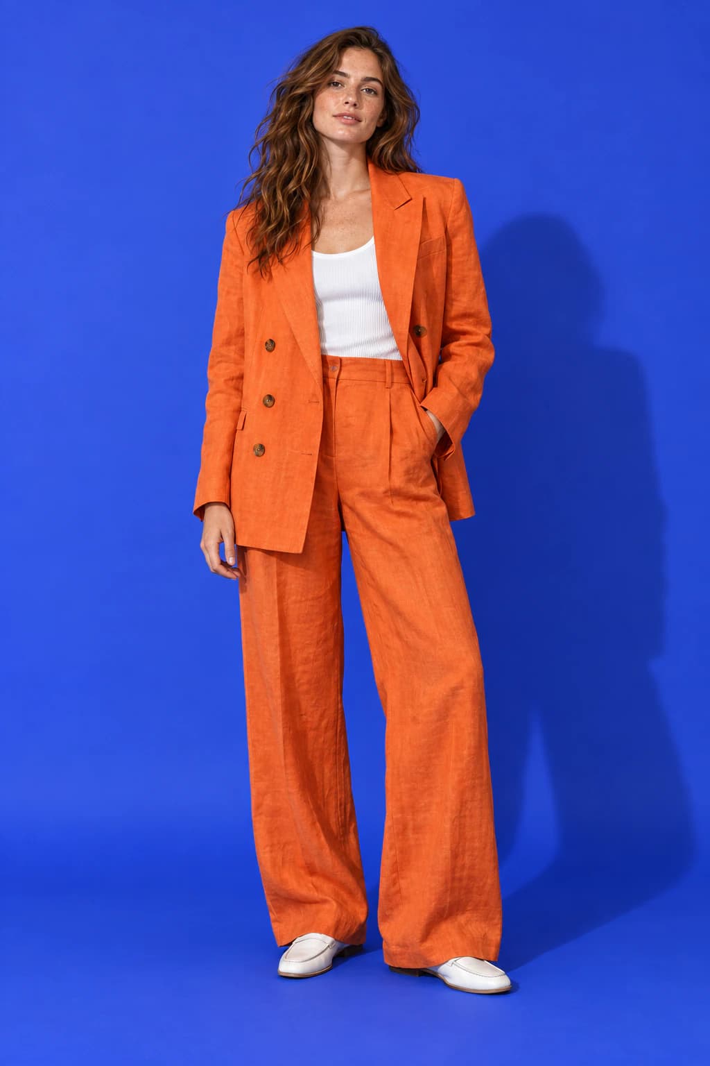 Model wearing the tangerine Riviera Linen Blazer on a cobalt backdrop